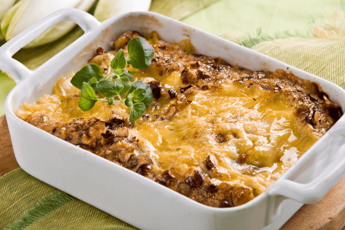 Cheesy Big Mac casserole garnished with fresh oregano in a white dish.