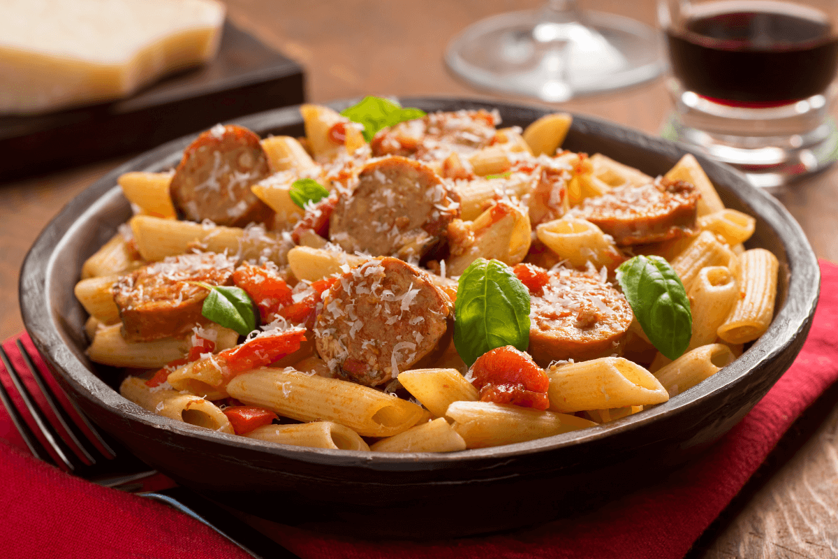 Hearty Kielbasa Pasta with parmesan and basil in a skillet.