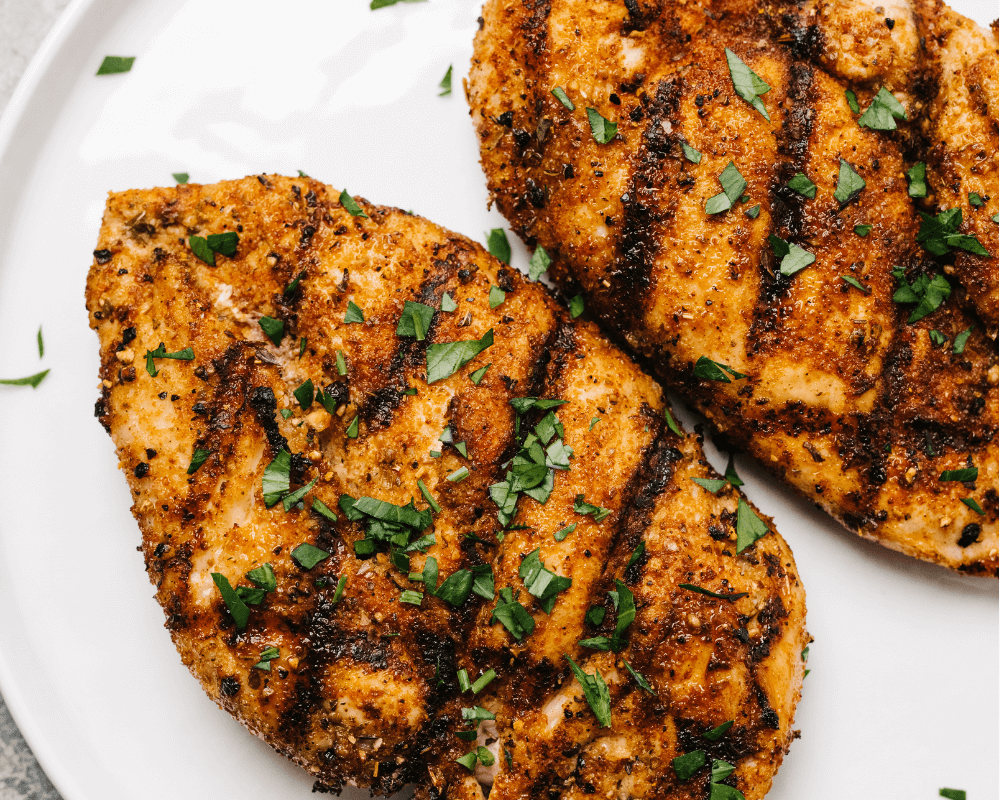 Seasoned blackened chicken tenders with parsley on a white plate.